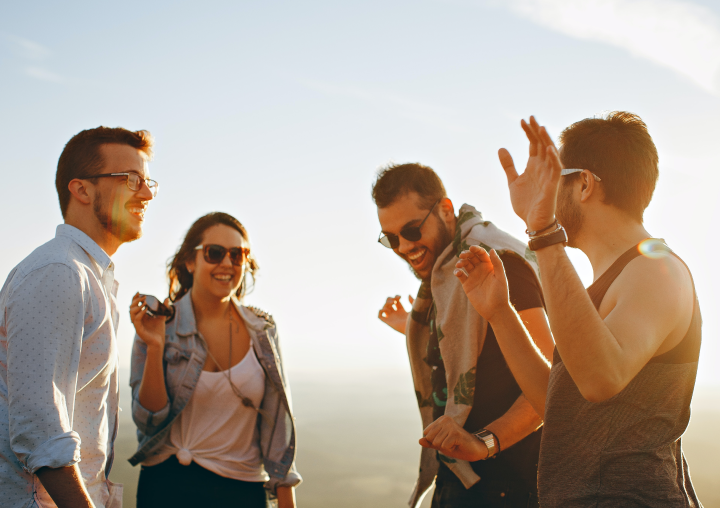 Four people hanging out on a mountaintop having a great time.